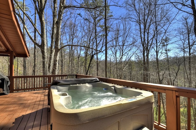 wooden terrace with a view of trees and a hot tub