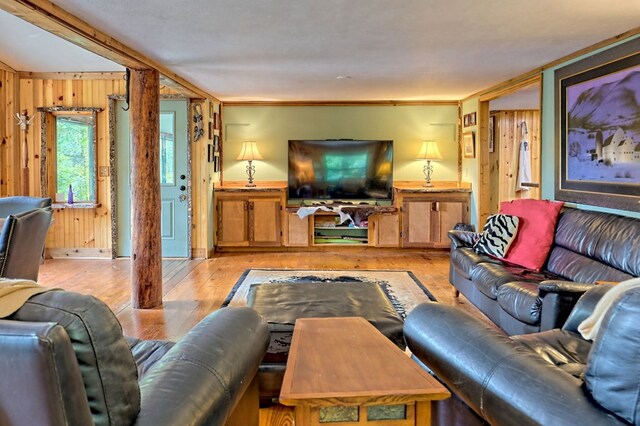 living room featuring ornamental molding, wood walls, and light hardwood / wood-style flooring