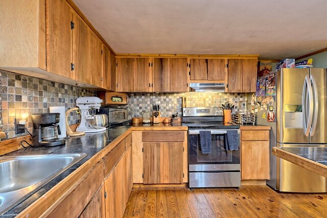 kitchen with crown molding, light hardwood / wood-style floors, stainless steel appliances, and tasteful backsplash