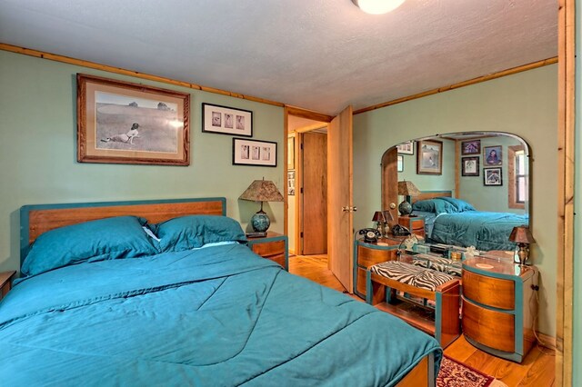 bedroom featuring a textured ceiling, crown molding, and light hardwood / wood-style floors