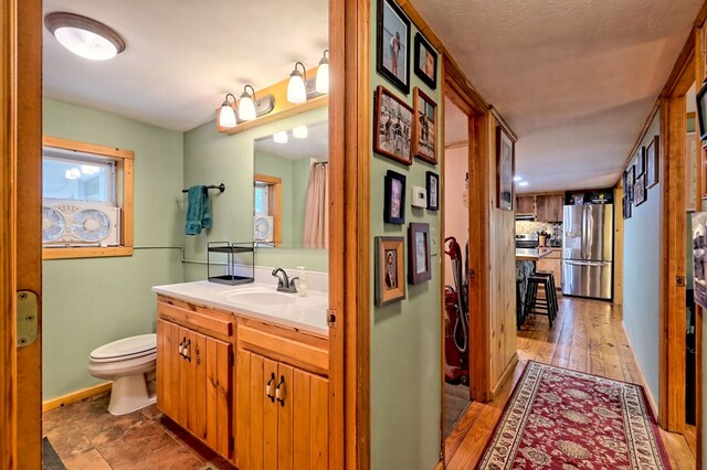 bathroom featuring decorative backsplash, vanity, a textured ceiling, hardwood / wood-style flooring, and toilet