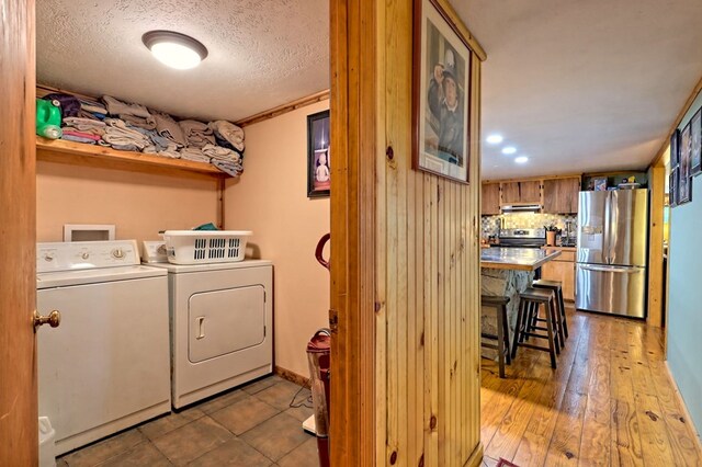 washroom with wood-type flooring, separate washer and dryer, and a textured ceiling