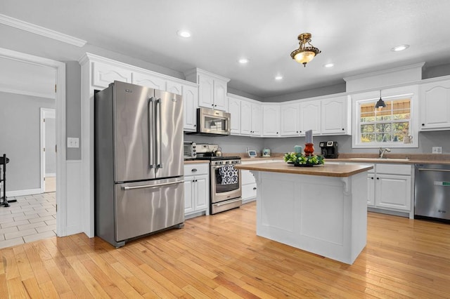 kitchen featuring stainless steel appliances, hanging light fixtures, and light hardwood / wood-style floors