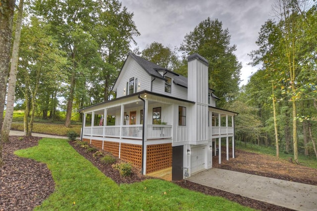 view of front of house featuring concrete driveway, a chimney, an attached garage, a porch, and board and batten siding