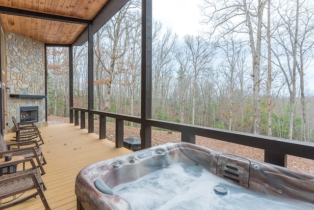 deck featuring an outdoor hot tub and a fireplace