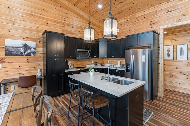 kitchen featuring sink, light stone counters, decorative light fixtures, a center island with sink, and appliances with stainless steel finishes