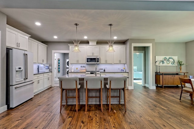 kitchen featuring white cabinets, decorative light fixtures, stainless steel appliances, and dark hardwood / wood-style floors