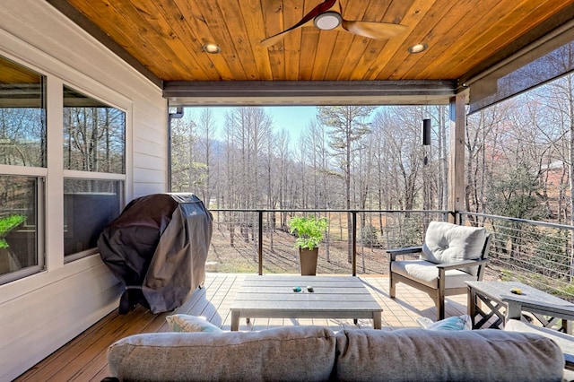 sunroom / solarium with ceiling fan, wooden ceiling, and a wealth of natural light