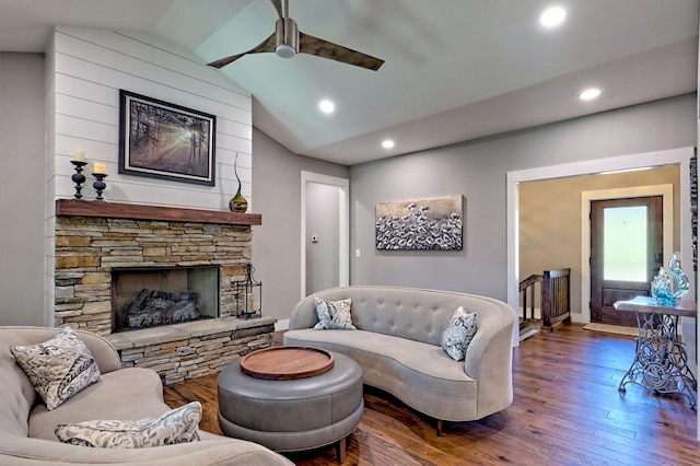 living room with a stone fireplace, ceiling fan, dark hardwood / wood-style flooring, and lofted ceiling