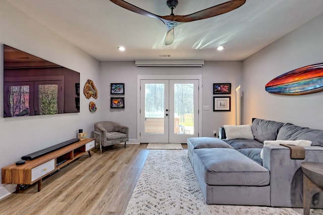 living room featuring a wall unit AC, ceiling fan, french doors, and light hardwood / wood-style floors