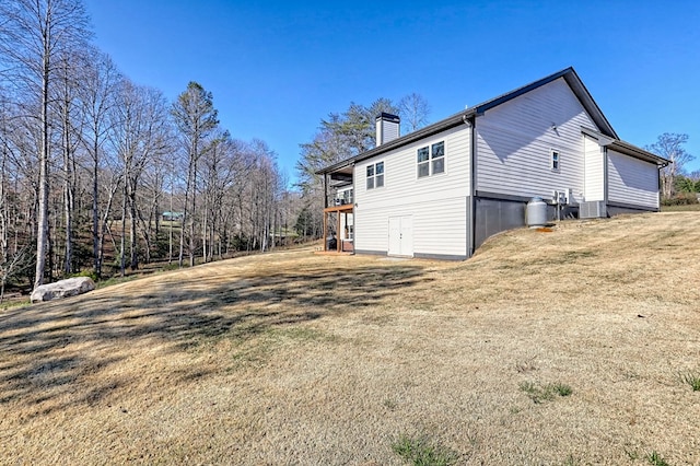 view of home's exterior featuring central AC unit, a wooden deck, and a lawn