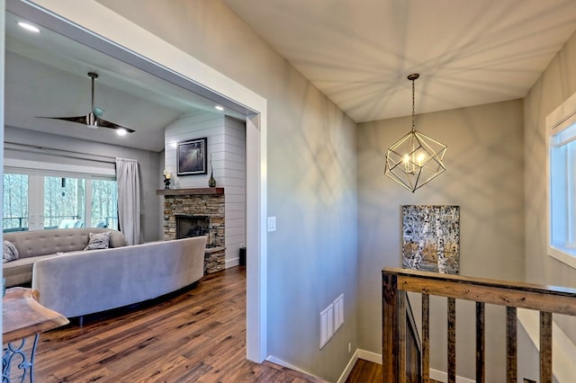 corridor with hardwood / wood-style floors, vaulted ceiling, and a notable chandelier