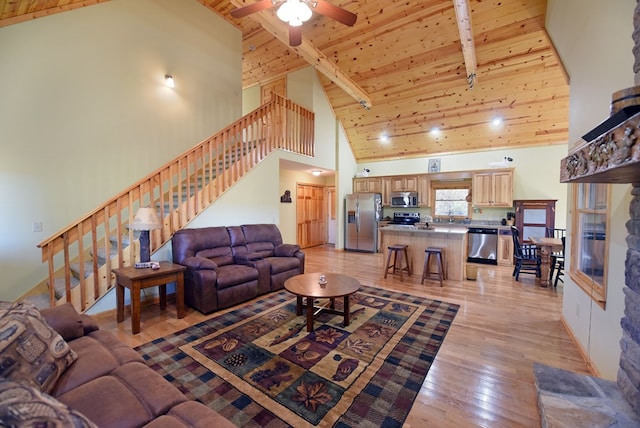 living room with ceiling fan, beam ceiling, light hardwood / wood-style flooring, high vaulted ceiling, and wooden ceiling