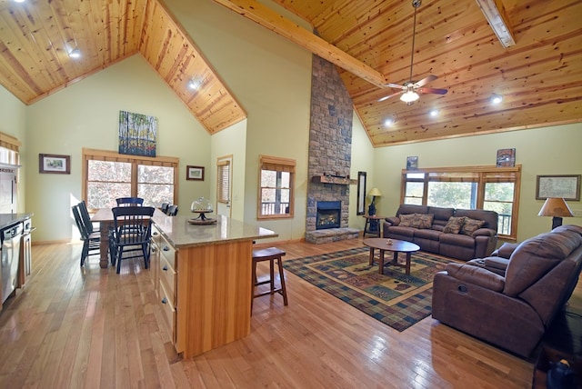 living room featuring high vaulted ceiling, light wood-type flooring, a fireplace, and wood ceiling