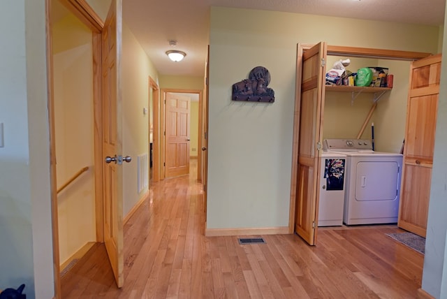 laundry area with washer and dryer, a textured ceiling, and light hardwood / wood-style floors