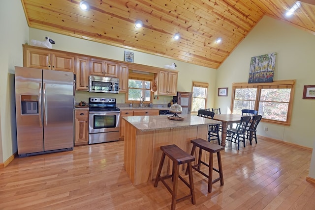 kitchen with light stone counters, wood ceiling, stainless steel appliances, sink, and light hardwood / wood-style flooring