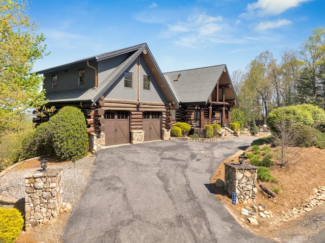 log-style house with aphalt driveway, stone siding, log exterior, and an attached garage