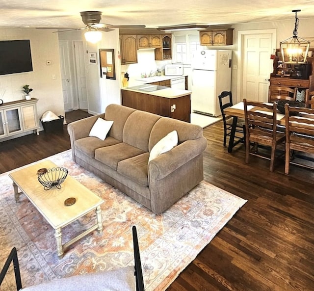 living room featuring sink, ceiling fan with notable chandelier, and dark wood-type flooring