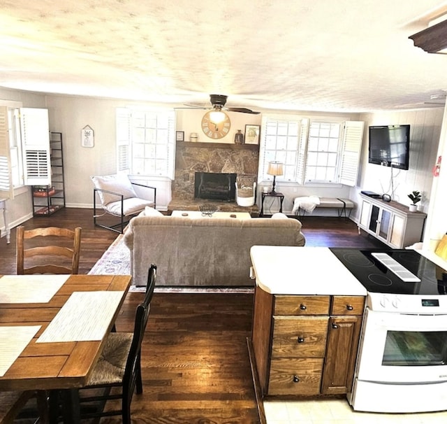 kitchen featuring ceiling fan, a stone fireplace, light hardwood / wood-style flooring, and white electric range