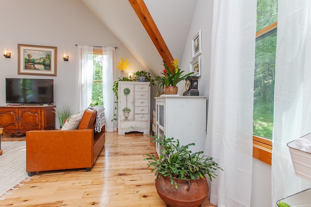 living room featuring beamed ceiling, high vaulted ceiling, and light hardwood / wood-style floors