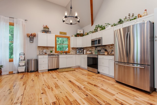 kitchen with decorative backsplash, white cabinets, appliances with stainless steel finishes, light hardwood / wood-style floors, and sink