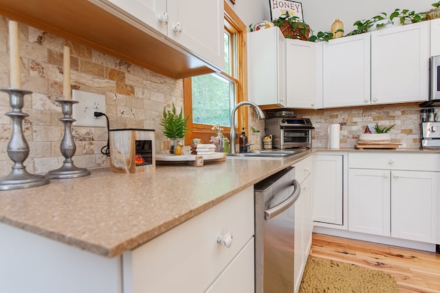 kitchen featuring light hardwood / wood-style floors, backsplash, stainless steel appliances, and white cabinets