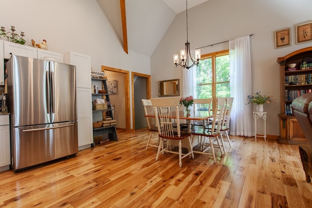 dining area featuring high vaulted ceiling, a notable chandelier, and light hardwood / wood-style floors