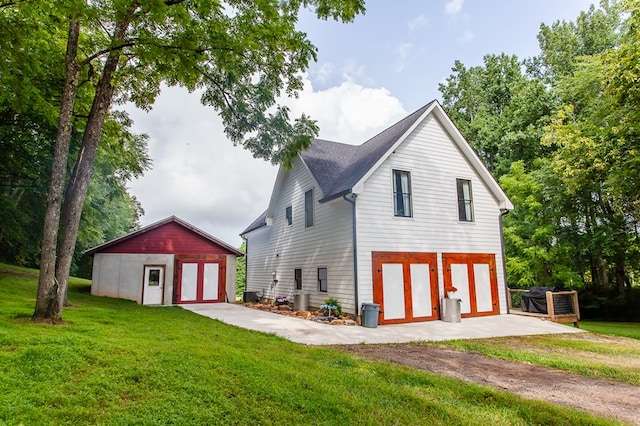 back of house featuring a lawn, a garage, and an outbuilding