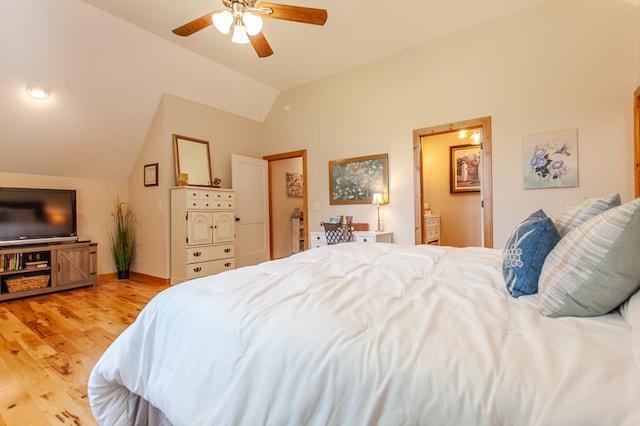 bedroom featuring ceiling fan, light hardwood / wood-style flooring, vaulted ceiling, and connected bathroom