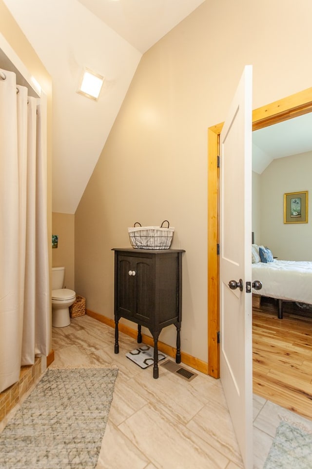 bathroom featuring wood-type flooring, toilet, and lofted ceiling