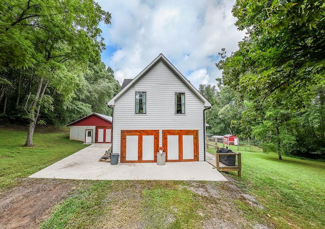 back of property featuring a yard, a patio area, and an outbuilding