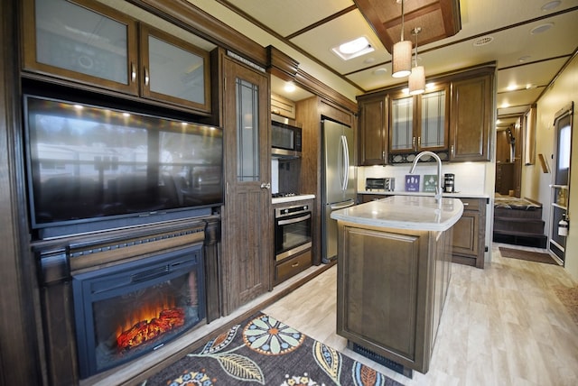 kitchen with a center island, hanging light fixtures, light wood-type flooring, appliances with stainless steel finishes, and decorative backsplash