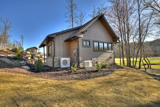 view of side of property with ac unit, a yard, and board and batten siding