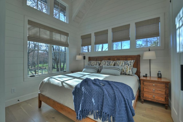 bedroom featuring baseboards, a towering ceiling, and wood finished floors