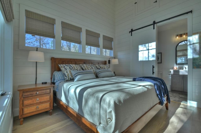 bedroom featuring light wood-style flooring and a barn door