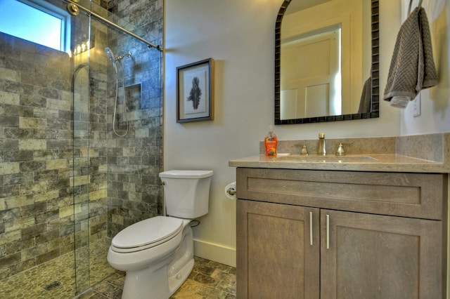 full bath featuring baseboards, toilet, a stall shower, stone finish floor, and vanity