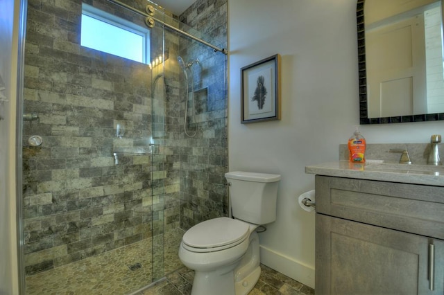 bathroom featuring baseboards, vanity, toilet, and a shower stall