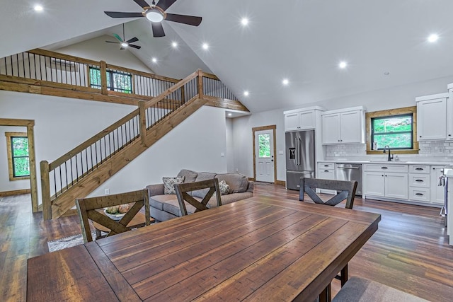 dining room with high vaulted ceiling, sink, ceiling fan, and dark wood-type flooring