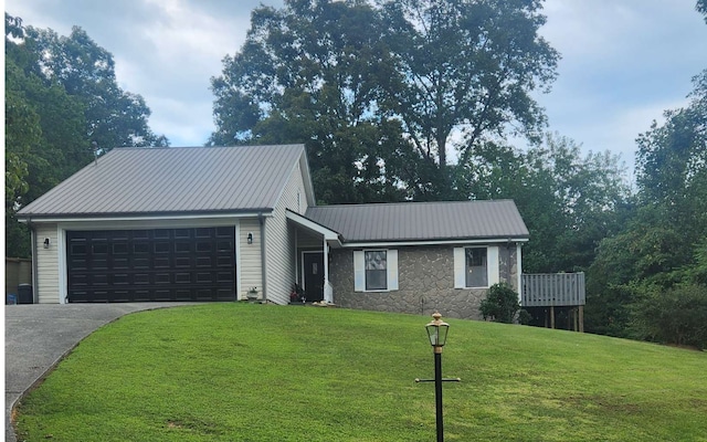 view of front of property with concrete driveway, an attached garage, a front lawn, stone siding, and metal roof