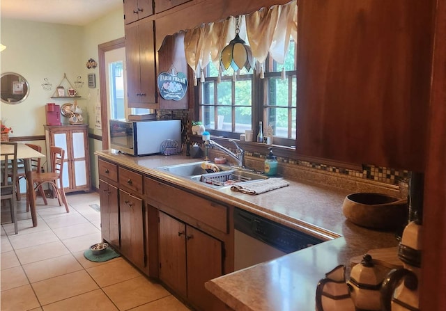 kitchen with appliances with stainless steel finishes, a sink, light tile patterned floors, tasteful backsplash, and light countertops