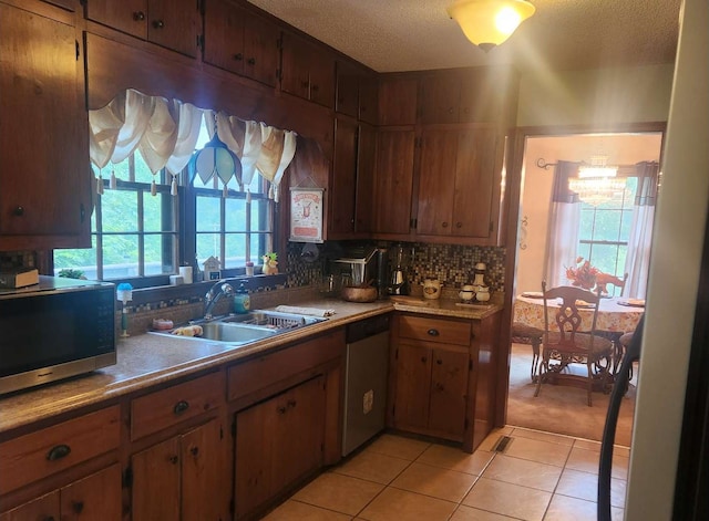 kitchen with appliances with stainless steel finishes, a sink, plenty of natural light, a textured ceiling, and light tile patterned floors