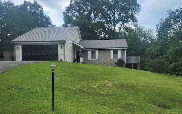 ranch-style home with an attached garage, asphalt driveway, a front yard, and metal roof