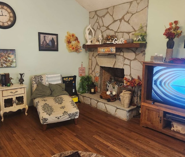 living area featuring wood-type flooring and a stone fireplace
