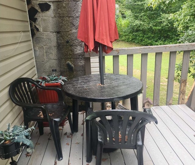 wooden deck with outdoor dining area and a lawn