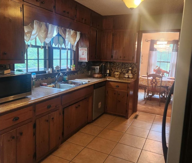 kitchen with stainless steel appliances, a sink, healthy amount of natural light, light tile patterned floors, and a textured ceiling