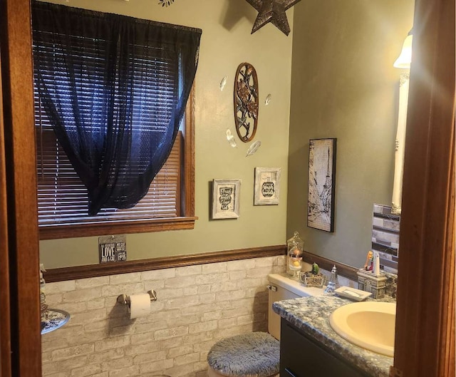 bathroom featuring vanity, a wainscoted wall, and toilet