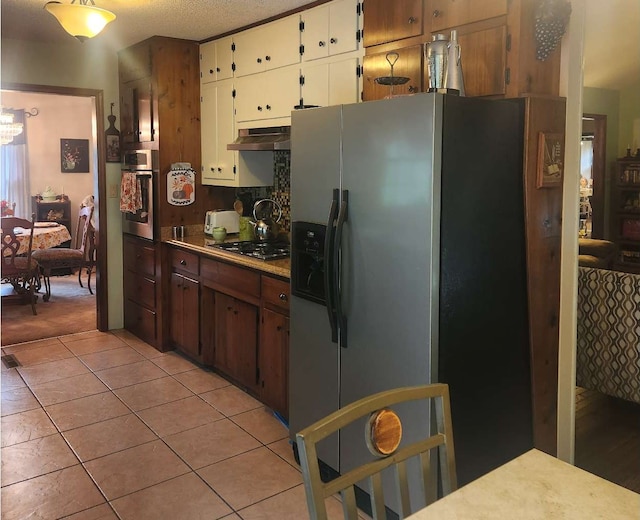 kitchen featuring stainless steel appliances, light tile patterned flooring, under cabinet range hood, white cabinets, and light countertops