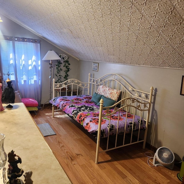 bedroom featuring wood finished floors and lofted ceiling