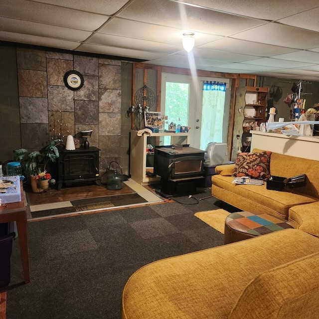 living room with a wood stove, carpet floors, and a paneled ceiling