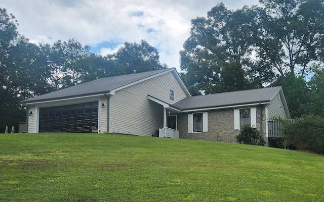 view of front of property with a garage, a front lawn, and metal roof